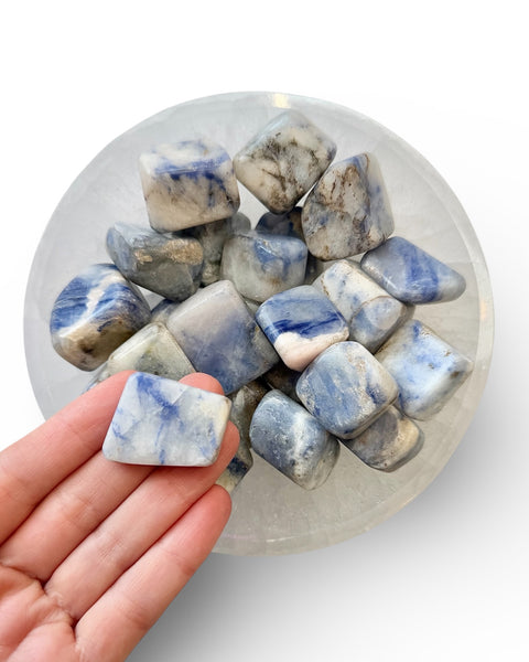 Blue and white afghanite tumble stone held in hand