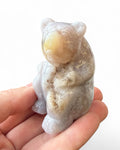Hand holding a small stone sculpture of a bear on a white background