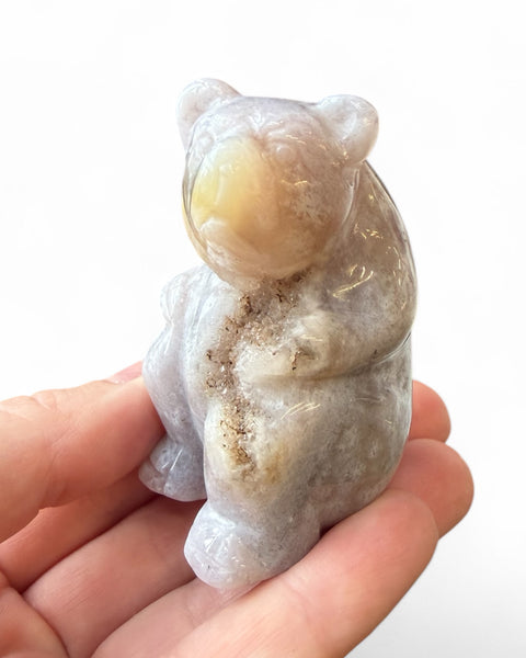 Hand holding a small stone sculpture of a bear on a white background