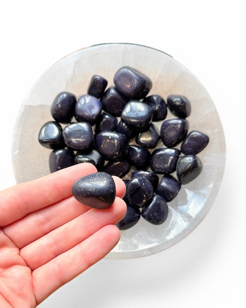 Hand holding blue goldstone tumble stone 
