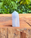 Crystal tower on a wooden surface with a blurred green foliage background