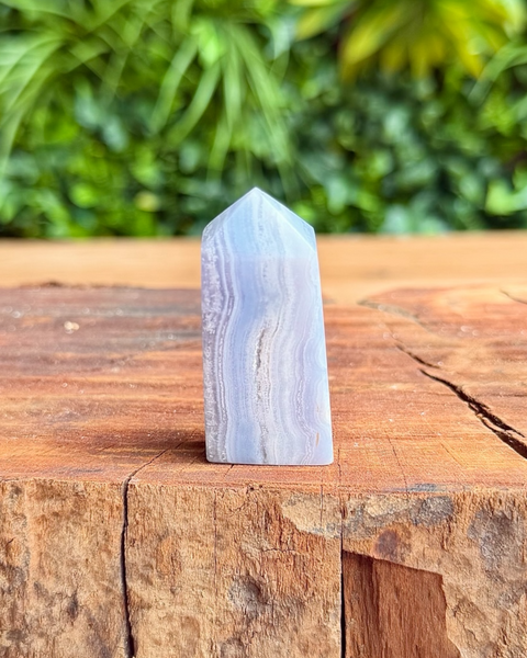 Crystal tower on a wooden surface with a blurred green foliage background