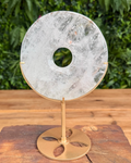 Decorative quartz stone disc on a brass stand with a natural background
