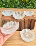 Clear glass bowls with a textured edge on a wooden block, held by a hand against a natural background.