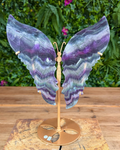 Carved fluorite butterfly wings on gold stand with natural purple and green banding.