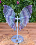 Fluorite butterfly wing carving on silver stand featuring purple and green tones.