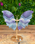 Fluorite butterfly carving on silver stand showing purple and green banding.