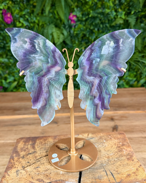 Decorative butterfly with iridescent wings on a wooden stand with a natural background