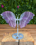 Fluorite butterfly wing carving on metal stand with natural purple and green layers.