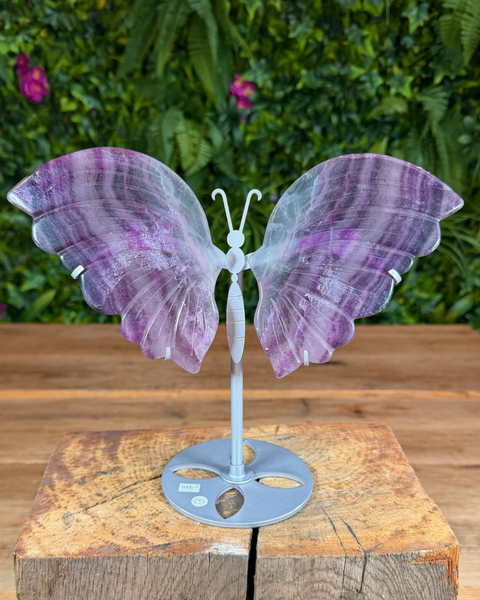 Fluorite butterfly wing carving on metal stand with natural purple and green layers.