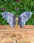 Purple and green fluorite butterfly wing carving on gold metal stand.