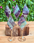 Decorative fluorite crystal pieces on gold stands with a natural background