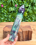 Multicolored crystal held by a hand with a natural background