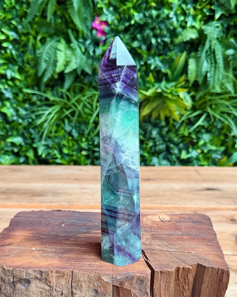 Multicolored crystal tower on a wooden surface with a green leafy background