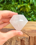 Hand holding a clear crystal against a natural background