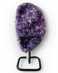 Amethyst crystal on a black stand against a white background