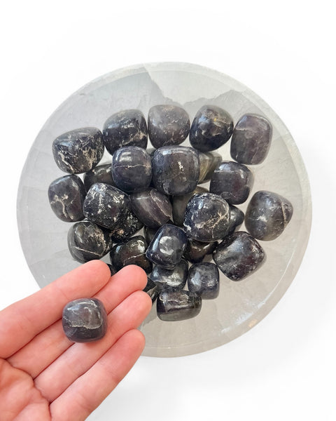 Hand holding iolite crystal tumble stone