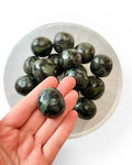 kambaba jasper tumble stone in hand