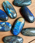 Blue and green labradorite gemstones on a wooden surface