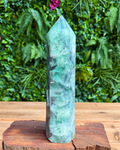 Green crystal tower on a wooden stand with a green leafy background