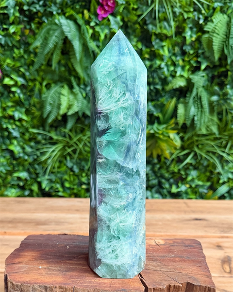 Green crystal tower on a wooden stand with a green leafy background