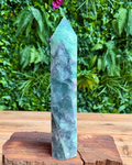 Green crystal tower on a wooden base with a green leafy background