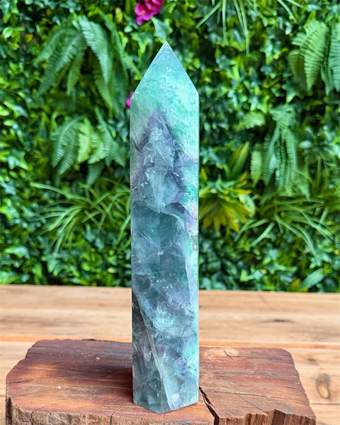 Green crystal tower on a wooden base with a green leafy background
