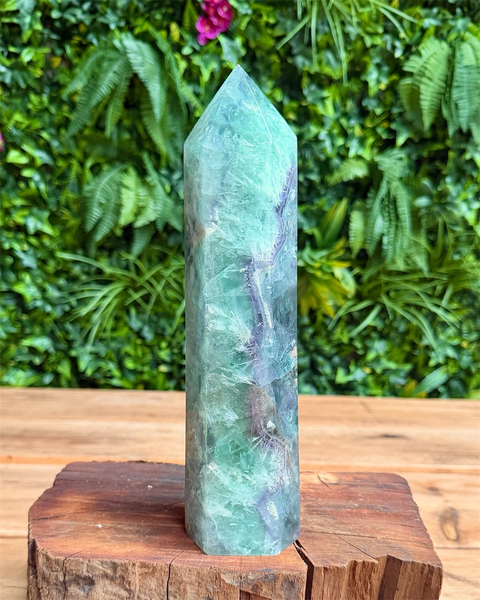 Green crystal tower on a wooden stand with a green leafy background