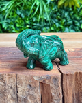 Green crystal elephant figurine on a wooden surface with a natural background