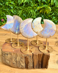 Set of five moon-shaped moonstone crystals on a wooden stand with a natural background