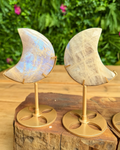 Two moon-shaped stone carvings on gold stands with a natural wood background