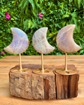 Three moon-shaped stone decorations on a wooden base with a natural background