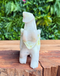 Carved crystal elephant on a wooden surface with green foliage in the background