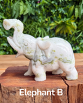 jade elephant carving on a wooden block with green foliage in the background