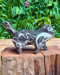 Decorative cat-shaped stone sculpture on a wooden block with a green foliage background