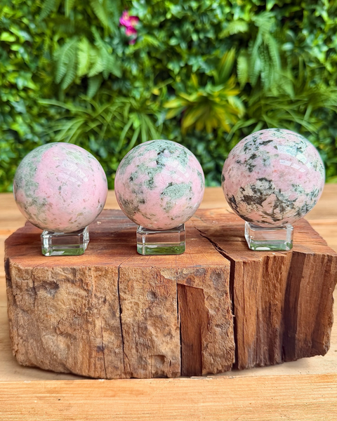 three pink and green crystal spheres a a row