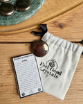 Pyrite prosperity coin with information card and 'Feel Good Crystals' pouch on a wooden surface