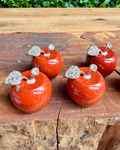 Four red jasper crystal apple-shaped  with silver leaves on a wooden surface