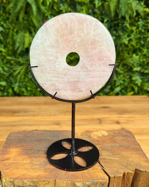 Round stone on a black stand with a green center, placed on a wooden surface with a blurred green background.
