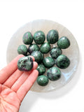 hand holding ruby zoisite tumble stone 