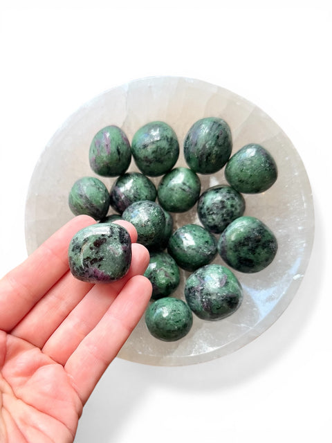 hand holding ruby zoisite tumble stone 
