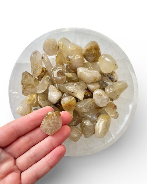 Hand holding a rutilated quartz tumble stone