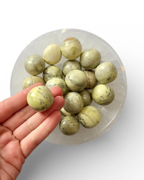 Hand holding a serpentine tumble stone