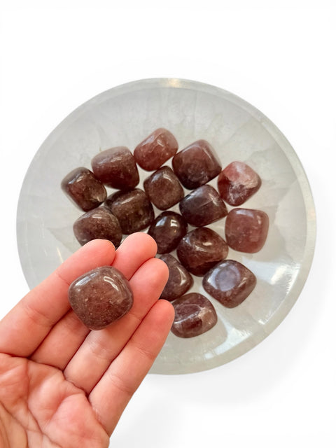 Hand holding strawberry quartz crystal tumble stone