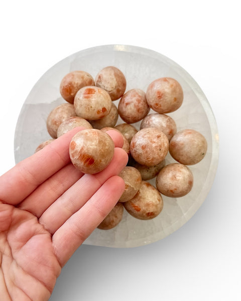 Hand holding a sunstone tumble stone