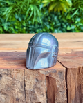 Helmet-like object on a wooden surface with green foliage in the background