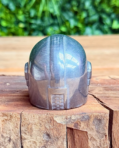 Metallic terahertz crystal head sculpture on a wooden surface with greenery in the background