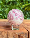 crystal sphere with pink inclusions on a stand