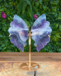 Fluorite butterfly wing carving on gold stand with natural purple and green banding.