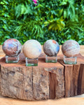 Four crystal moonstone spheres on a wooden stand with a natural background
